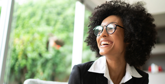 A woman smiling happily while looking at the window.